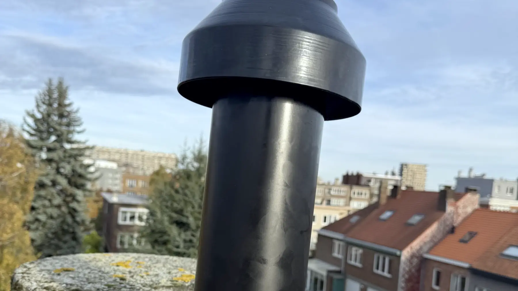 Rookgasafvoer van een ketel op een dak, met zicht op de daken